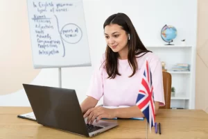 Professora durante aula particular de inglês com bandeira britânica ao fundo.